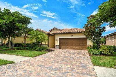 20635 Romagna Pl, Venice, FL 34293 - mediterranean / spanish home featuring an attached garage, decorative driveway, stucco siding, a tile roof, and a front yard