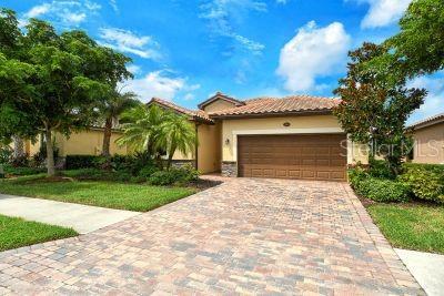 20635 Romagna Pl, Venice, FL 34293 - mediterranean / spanish home with a garage, decorative driveway, stucco siding, a tiled roof, and a front lawn