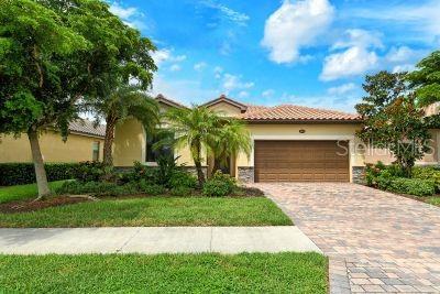 20635 Romagna Pl, Venice, FL 34293 - mediterranean / spanish house featuring an attached garage, decorative driveway, stucco siding, a tiled roof, and a front lawn