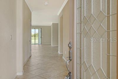 corridor with light tile patterned floors and ornamental molding