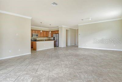 unfurnished living room featuring light tile patterned flooring and ornamental molding