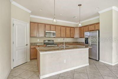 20635 Romagna Pl, Venice, FL 34293 - kitchen featuring appliances with stainless steel finishes, crown molding, a sink, light tile patterned flooring, and pendant lighting