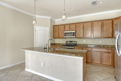 20635 Romagna Pl, Venice, FL 34293 - kitchen featuring stainless steel appliances, crown molding, a sink, light tile patterned floors, and dark stone counters