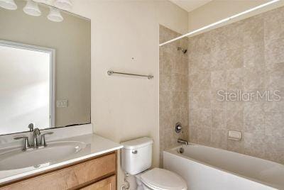 full bathroom featuring tiled shower / bath combo, toilet, and vanity