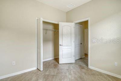 unfurnished bedroom featuring a closet and light tile patterned floors