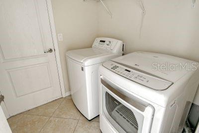 laundry room featuring washing machine and dryer and light tile patterned flooring