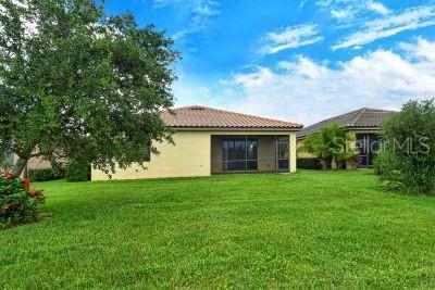 20635 Romagna Pl, Venice, FL 34293 - rear view of property featuring stucco siding, a yard, a tiled roof, and a sunroom