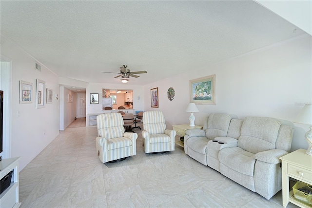 living room featuring ceiling fan and a textured ceiling