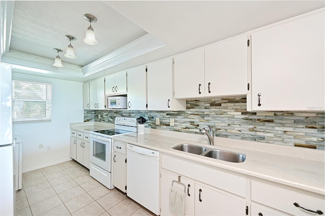 kitchen featuring white appliances, sink, hanging light fixtures, a tray ceiling, and white cabinetry