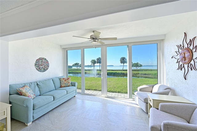 living room featuring plenty of natural light, ceiling fan, and a water view