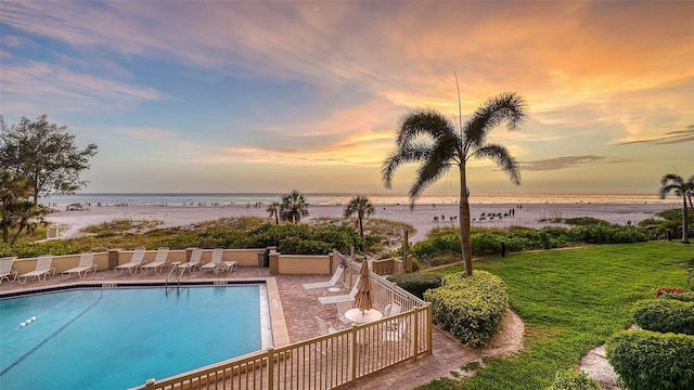 pool at dusk with a yard and a water view