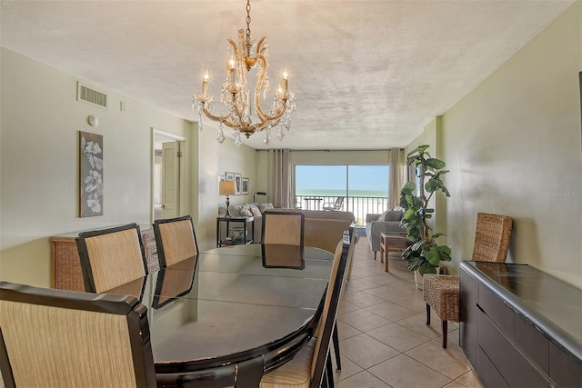 tiled dining area featuring a textured ceiling and a chandelier