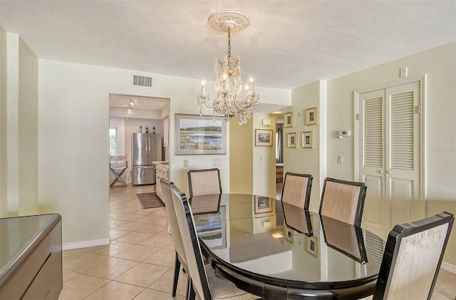 dining area with a textured ceiling, an inviting chandelier, and light tile patterned floors