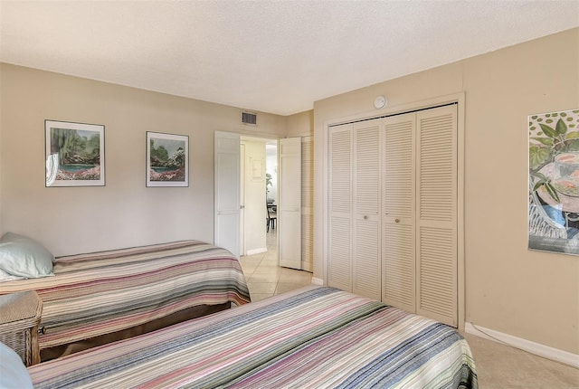 bedroom with light tile patterned floors, a closet, and a textured ceiling