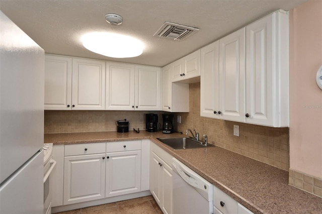 kitchen with backsplash, white appliances, white cabinets, and sink