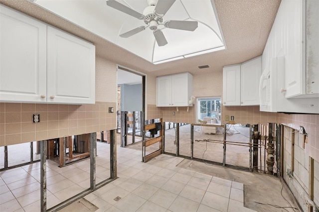 kitchen featuring white cabinets, a textured ceiling, light tile patterned floors, and ceiling fan