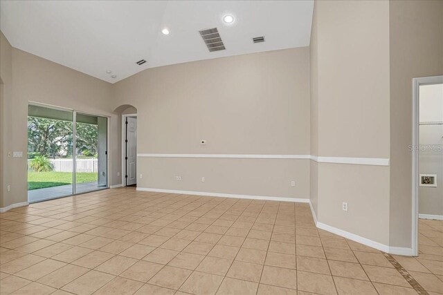 empty room with light tile patterned floors and high vaulted ceiling