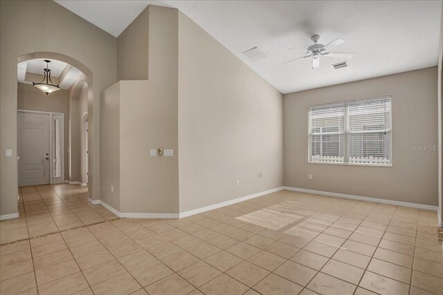 empty room featuring ceiling fan, vaulted ceiling, and light tile patterned floors