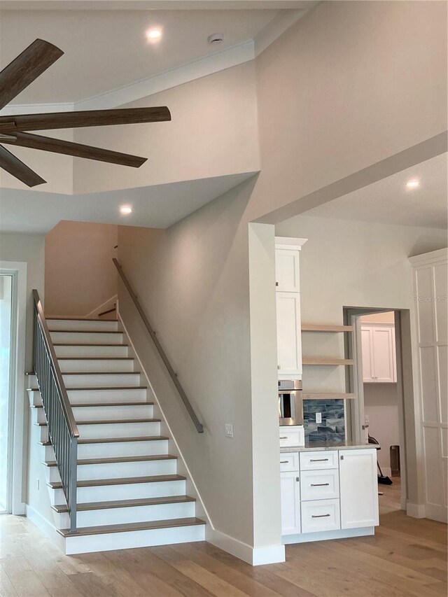 staircase featuring wood-type flooring and crown molding