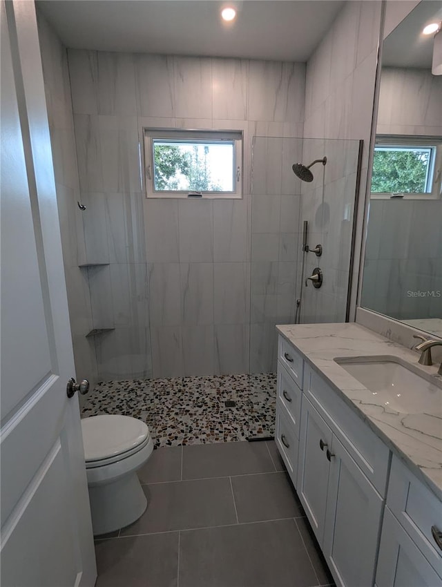 bathroom featuring tile patterned floors, vanity, a healthy amount of sunlight, and a tile shower