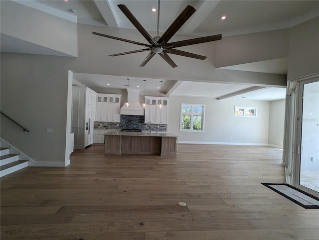 kitchen featuring beam ceiling, white cabinetry, a large island, hardwood / wood-style floors, and custom range hood