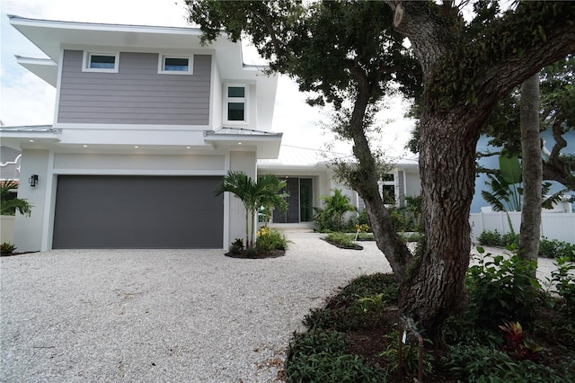4819 Higel Rd, Sarasota, FL 34242 - view of front of property with gravel driveway, an attached garage, stucco siding, a standing seam roof, and metal roof