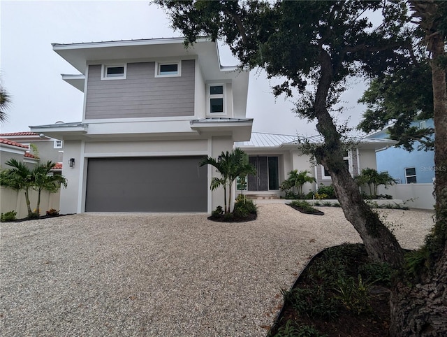 view of front of house with driveway, metal roof, an attached garage, a standing seam roof, and fence