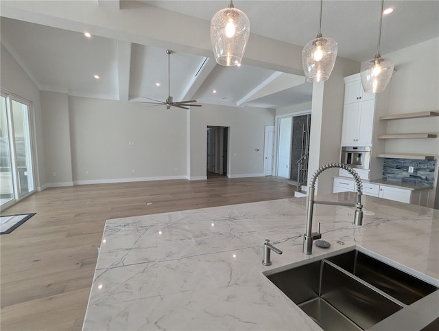 kitchen with vaulted ceiling with beams, light stone counters, and sink