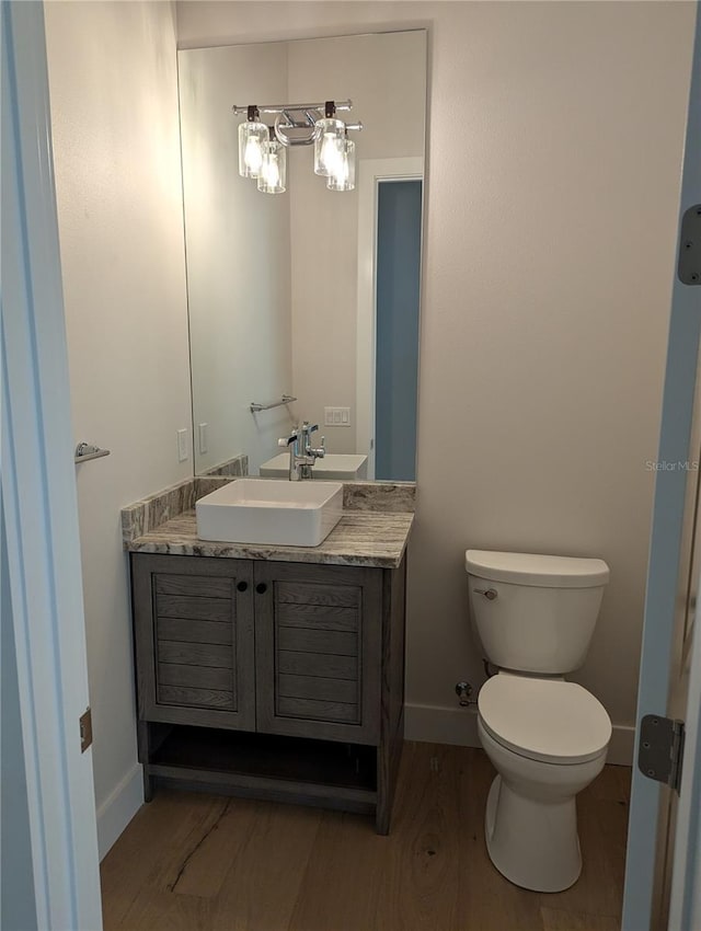 bathroom with wood-type flooring, vanity, and toilet