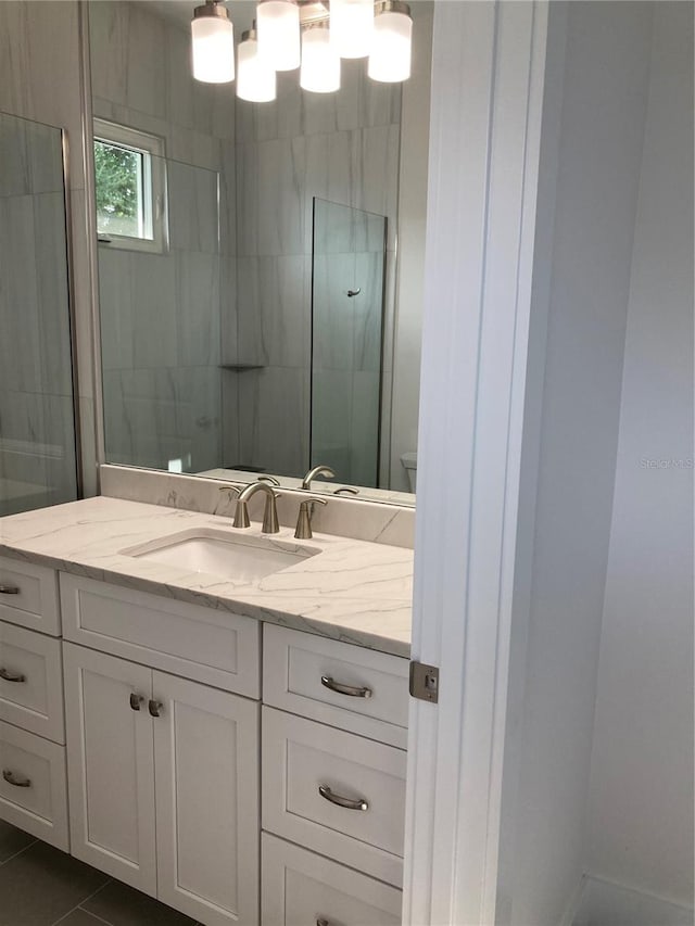 bathroom featuring a tile shower, tile patterned floors, vanity, and toilet