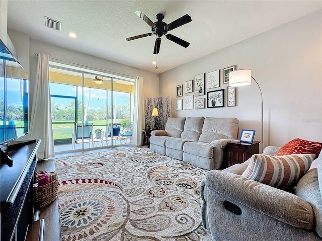 living room with ceiling fan and a textured ceiling