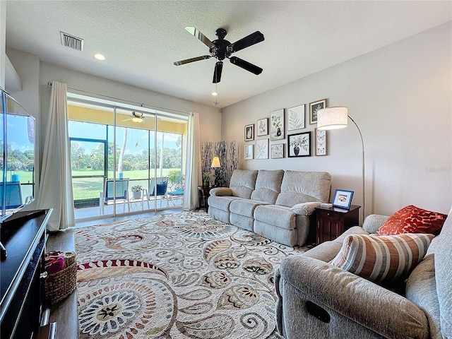 living room with a textured ceiling and ceiling fan