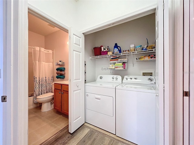 laundry room featuring washing machine and clothes dryer and light hardwood / wood-style floors