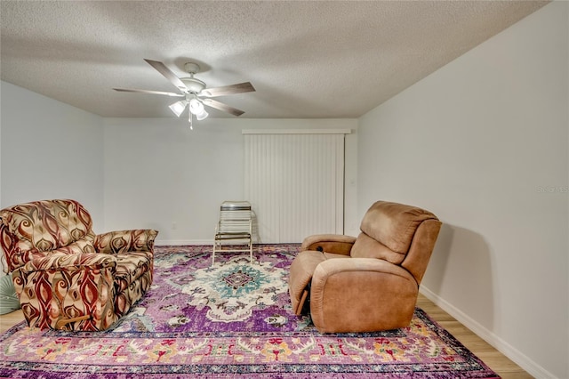 living room with light wood-type flooring, a textured ceiling, and ceiling fan