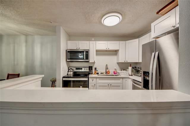 kitchen featuring sink, stainless steel appliances, a textured ceiling, and white cabinets