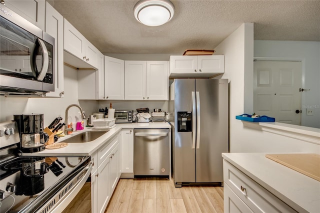 kitchen with white cabinetry, appliances with stainless steel finishes, sink, and light hardwood / wood-style floors