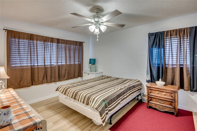 bedroom with ceiling fan, a textured ceiling, and hardwood / wood-style flooring