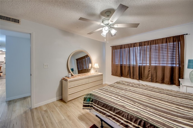 bedroom featuring ceiling fan, light wood-type flooring, and a textured ceiling