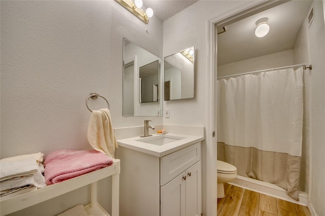 bathroom with a textured ceiling, toilet, hardwood / wood-style floors, and vanity