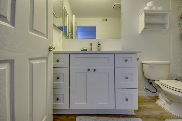 bathroom with toilet, hardwood / wood-style floors, and vanity