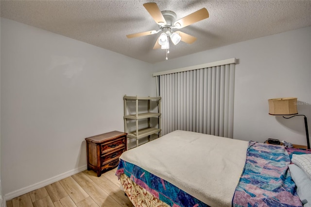 bedroom with a textured ceiling, ceiling fan, and light hardwood / wood-style floors