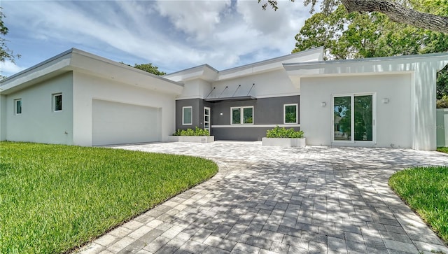 view of front of home featuring a garage, decorative driveway, a front yard, and stucco siding