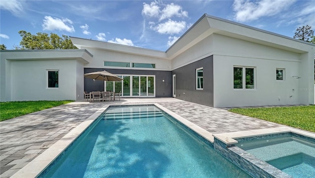 back of house with a pool with connected hot tub, a patio, and stucco siding