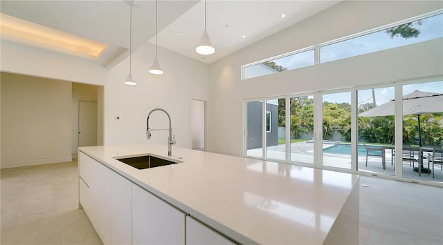 kitchen featuring sink, high vaulted ceiling, light tile patterned floors, pendant lighting, and white cabinets