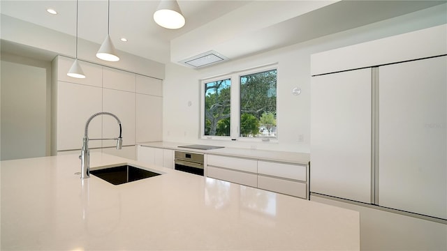 kitchen featuring sink, white cabinets, hanging light fixtures, and stainless steel oven