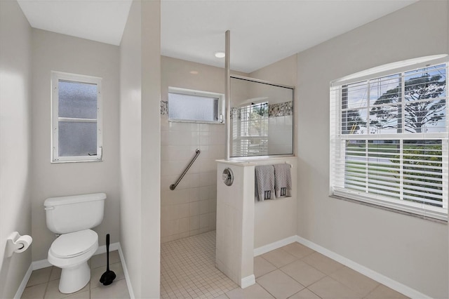 bathroom with tile patterned flooring, toilet, and tiled shower