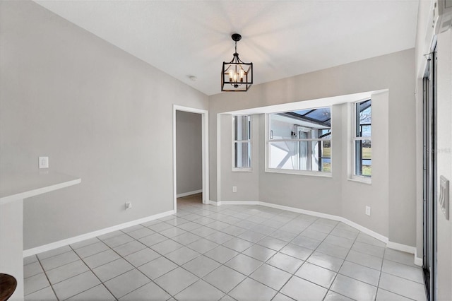 tiled empty room featuring an inviting chandelier and vaulted ceiling