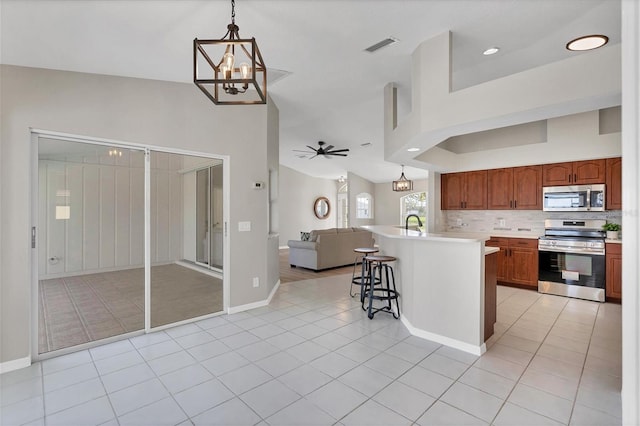 kitchen featuring appliances with stainless steel finishes, ceiling fan with notable chandelier, a breakfast bar, and decorative light fixtures