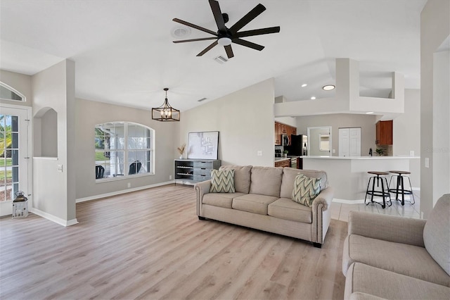 living room featuring light wood-type flooring, ceiling fan with notable chandelier, and lofted ceiling