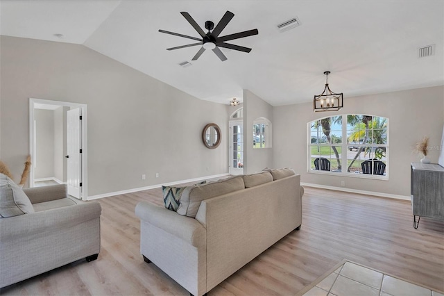 living room with light wood-type flooring, ceiling fan with notable chandelier, and lofted ceiling